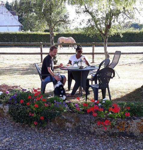 a man and woman sitting at a table with a dog at La PASTORALE in La Puisaye