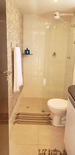 a white bathroom with a toilet and a shower at Flat 14 Pipa in Pipa