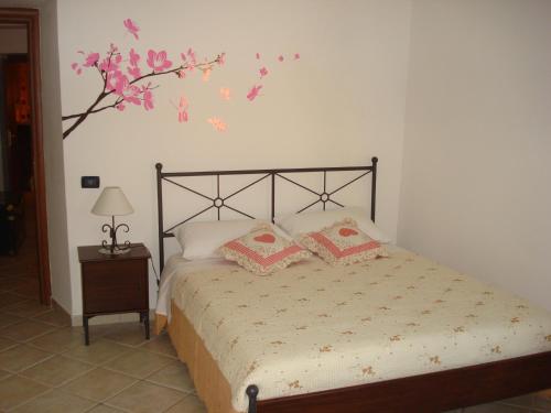 リエーティにあるLa Casetta dei Sogniのベッドルーム1室(ピンクの花が飾られた壁のベッド1台付)