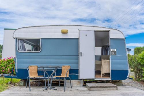 a blue and white caravan with a table and chairs at Leithfield Beach Holiday Park in Leithfield