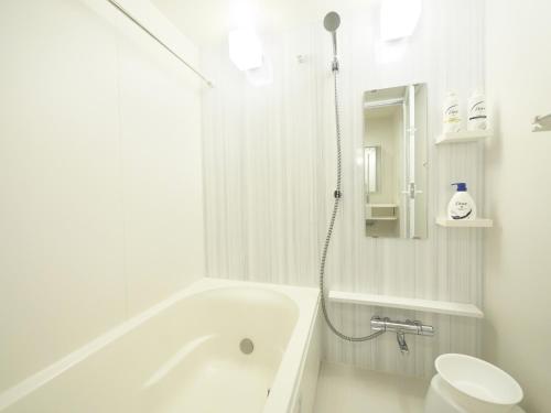 a white bathroom with a tub and a toilet at ケイアイコンホテルズ ふくしあ801 in Chikusachō