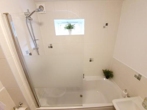 baño blanco con ducha y lavamanos en Accommodation in Stevenage 2 bedrooms, en Stevenage