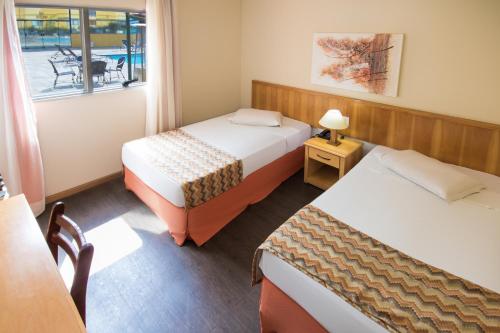 Habitación con 2 camas, mesa y ventana en Hotel Nacional Inn Sorocaba, en Sorocaba