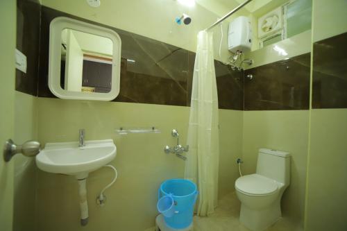 een badkamer met een wastafel, een toilet en een spiegel bij Taj homes stay in Tirupati