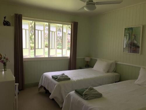 a bedroom with two beds and a window with towels on them at CedarBrae Country Stay in Gympie