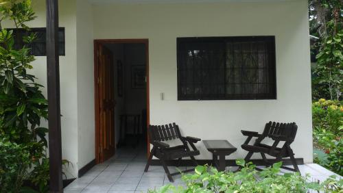 two chairs and a table on a porch of a house at Hotel Arboleda in Quepos