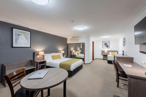 Best Western Plus Ambassador Orange في أورنج: غرفة في الفندق بسرير ومكتب وطاولة
