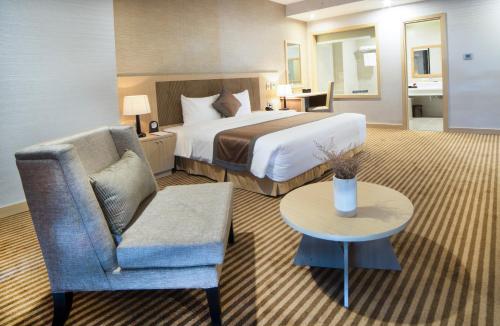a hotel room with a bed and a chair and a table at Muong Thanh Luxury Vientiane Hotel in Vientiane