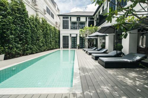 a swimming pool with chaise lounge chairs next to a building at 99 The Heritage Hotel in Chiang Mai