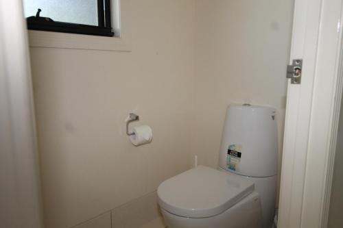 a white bathroom with a toilet and a window at Nirvana in Tangalooma
