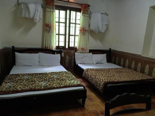 two beds in a room with windows and curtains at Duong Sat Hotel in Khu Chi Lăng
