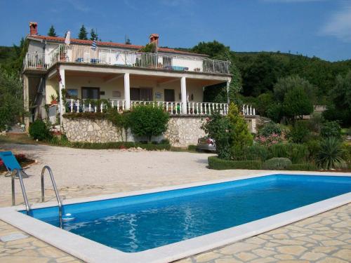 a villa with a swimming pool in front of a house at Comfortable holiday home in Labin in Drenje