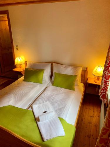 a bed with green and white pillows and two lamps at Das Alpl Resort in Krieglach