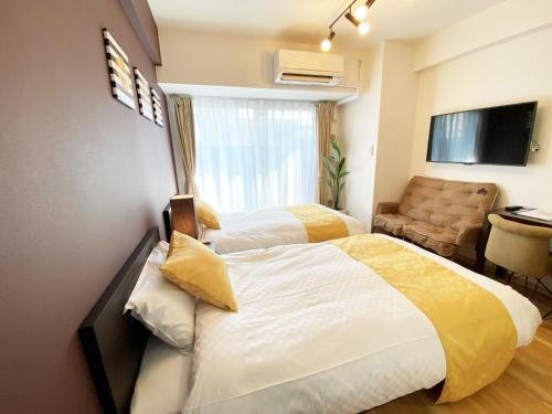 a hotel room with two beds and a chair at @RLiS_house大阪ドームシティ in Osaka