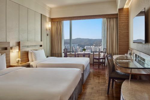 a hotel room with two beds and a table at Nina Hotel Tsuen Wan West in Hong Kong