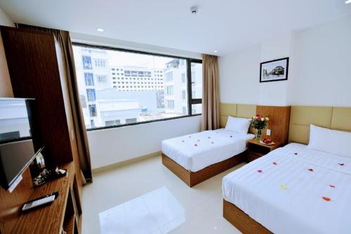 um quarto de hotel com duas camas e uma grande janela em Alibaba em Nha Trang