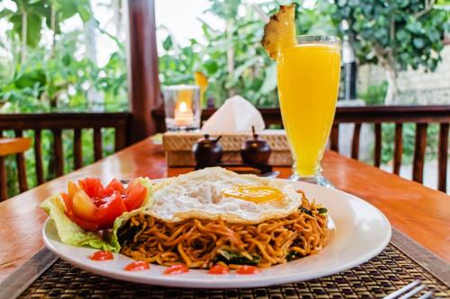een bord spaghetti met een ei en een glas sinaasappelsap bij Alam Selumbung Garden in Nusa Penida
