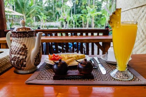 een tafel met een bord eten en een glas sinaasappelsap bij Alam Selumbung Garden in Nusa Penida