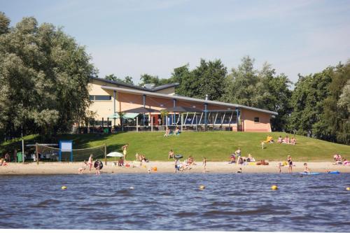 a group of people on a beach near the water at VakantieNoord, chalet 6p with veranda, located in Friesland, 5 stars camping on the lake in Suameer