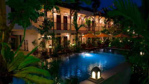 a swimming pool in front of a building at night at Montra Nivesha Residence in Siem Reap
