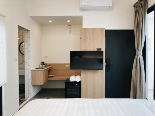 ein Hotelzimmer mit einem Bett und einem Flachbild-TV in der Unterkunft Belly Inn Douliu in Douliu