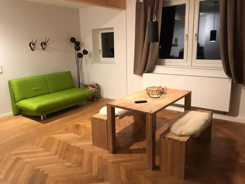 ein Wohnzimmer mit einem grünen Sofa und einem Tisch in der Unterkunft WAGNERS Ferienwohnungen in Norhalben in Nordhalben