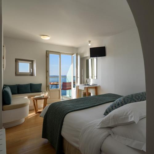 a bedroom with a bed and a view of the ocean at Panorama Boutique Hotel in Fira