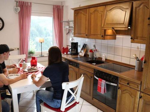 Ein Mann und eine Frau sitzen an einem Tisch in einer Küche in der Unterkunft Ferienwohnung Voege in Schmallenberg