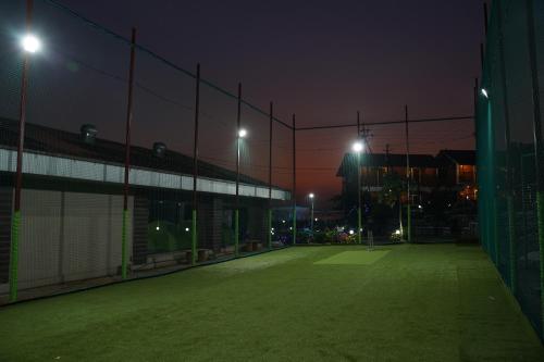 an empty tennis court at night with lights on at Relax Adventure Resort in Igatpuri