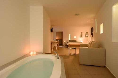 a large bath tub in a room with a living room at Panorama Boutique Hotel in Fira