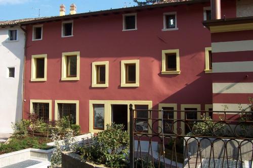 a red building with yellow windows and a fence at Residence Villa Vinco in Tregnago