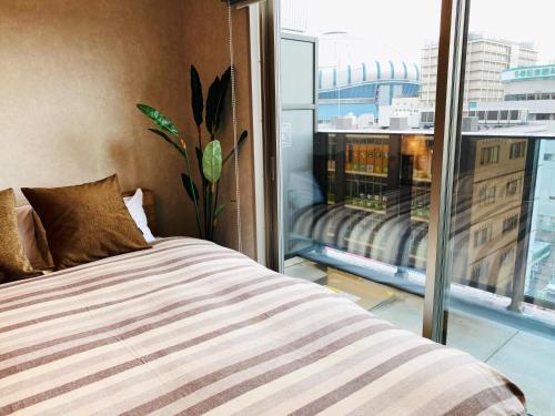 a bedroom with a bed and a large window at @RLiS_house大阪ドームシティ in Osaka