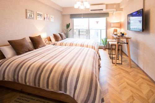 a bedroom with two beds and a table at @RLiS_house大阪ドームシティ in Osaka