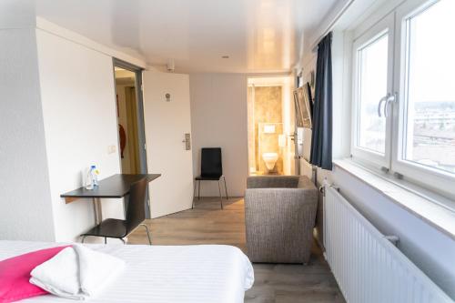 a bedroom with a bed and a desk and a window at Huis Ter Geul in Valkenburg