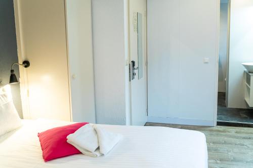 a bed with a red and white pillow on it at Huis Ter Geul in Valkenburg