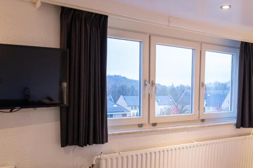 a room with three windows and a television on a wall at Huis Ter Geul in Valkenburg