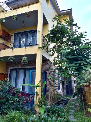 an apartment building with a balcony and a garden at Pink Tulip Hoi An in Hoi An