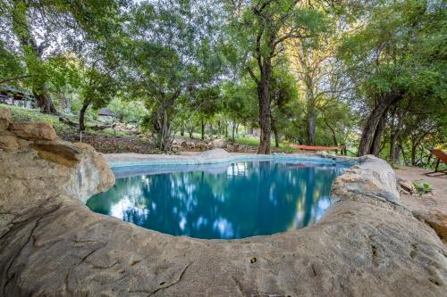 a pool of blue water with trees in the background at Umlani Bushcamp in Timbavati Game Reserve