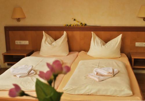 two beds in a hotel room with towels and flowers at Gasthof Kampenwand Aschau in Aschau im Chiemgau