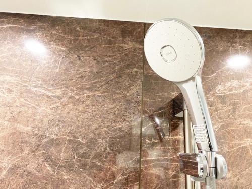 a shower head in a bathroom with a marble floor at @RLiS_house大阪ドームシティ in Osaka