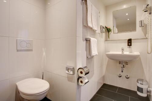 a white bathroom with a toilet and a sink at Boutique 003 Köln City am Dom, Trademark Collection by Wyndham in Cologne