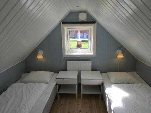 two beds in a room with a table and a window at DeLay's Guest House in Ängelholm