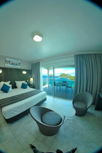 a bedroom with a bed and a view of the ocean at Hôtel Bois Joli in Terre-de-Haut