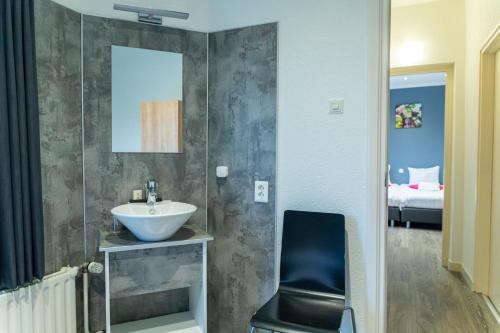 a bathroom with a sink and a chair in a room at Huis Ter Geul in Valkenburg