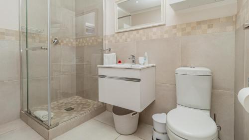 a bathroom with a toilet and a glass shower at Sea Breeze Guest House in Bloubergstrand