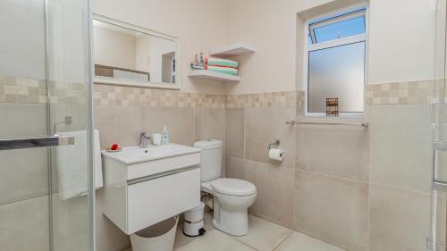 ein Badezimmer mit einem WC, einem Waschbecken und einem Spiegel in der Unterkunft Sea Breeze in Bloubergstrand