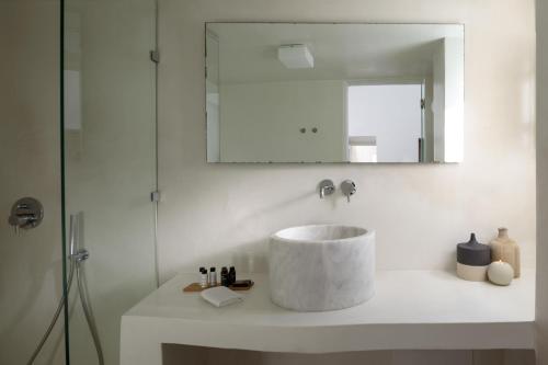 a white bathroom with a sink and a mirror at Panorama Suites in Fira