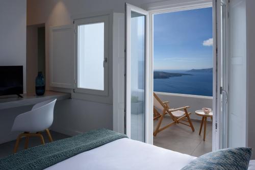 a bedroom with a bed and a view of the ocean at Panorama Suites in Fira