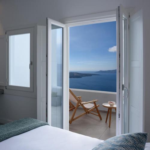 a bedroom with a bed and a view of the ocean at Panorama Suites in Fira