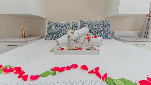 a white bed with a bottle of wine and flowers on it at Sea Breeze in Bloubergstrand